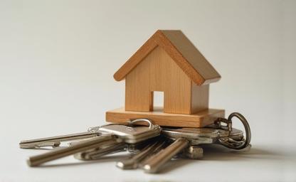 Close-up view of a small wooden model house positioned on a stack of keys, symbolizing the process of obtaining a home loan in India.