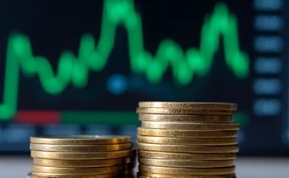 Close-up of a financial bar graph displayed on a screen, with stacks of Indian Rupee coins in the foreground, representing investment in mutual funds.